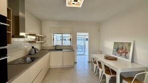 A modern kitchen with white cabinets, a black countertop, and a window overlooking a stone patio. - Cruzeiro by Check-in Portugal (Quarteira)