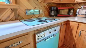 Una cocina con estufa antigua, microondas y armarios de madera.