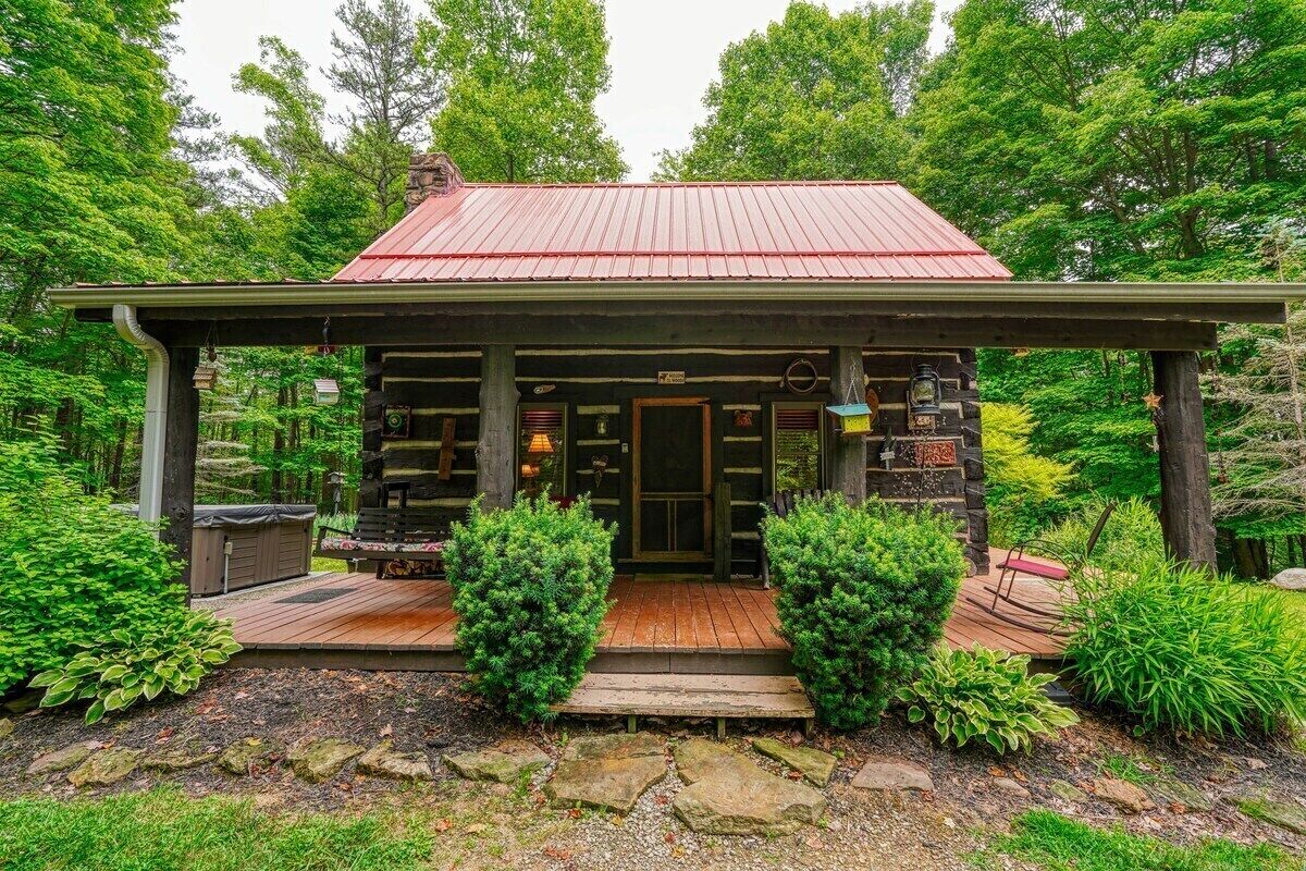 Een rustieke houten chalet met een terras, een metalen dak en een stenen fundering.