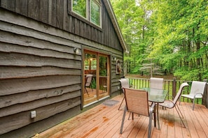 A wooden cabin with a deck, glass sliding doors, and outdoor seating.