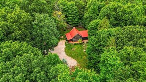 Ilmakuva mökistä, jonka ympärillä on tiheä metsä.