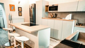 Una cocina moderna con una isla central, taburetes de bar, un refrigerador y un microondas.