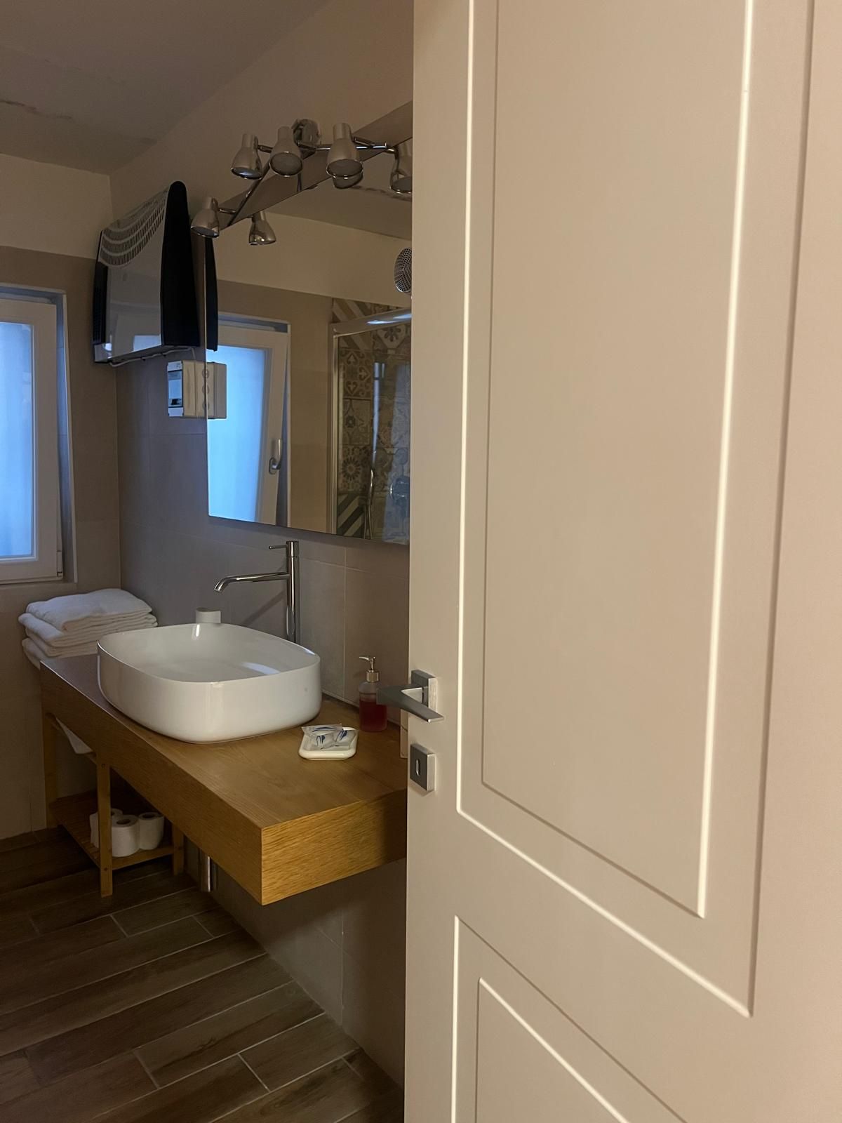 A bathroom with a white sink, a mirror, a towel rack, and a shower area.