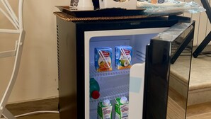 A compact refrigerator with a coffee maker and a tray of snacks. Inside, there are cartons of milk and a bottle of juice. - Domus Antica (Santa Maria Capua Vetere)