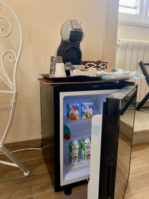 A compact refrigerator with a coffee maker and a tray of snacks. Inside, there are cartons of milk and a bottle of juice. - Domus Antica (Santa Maria Capua Vetere)