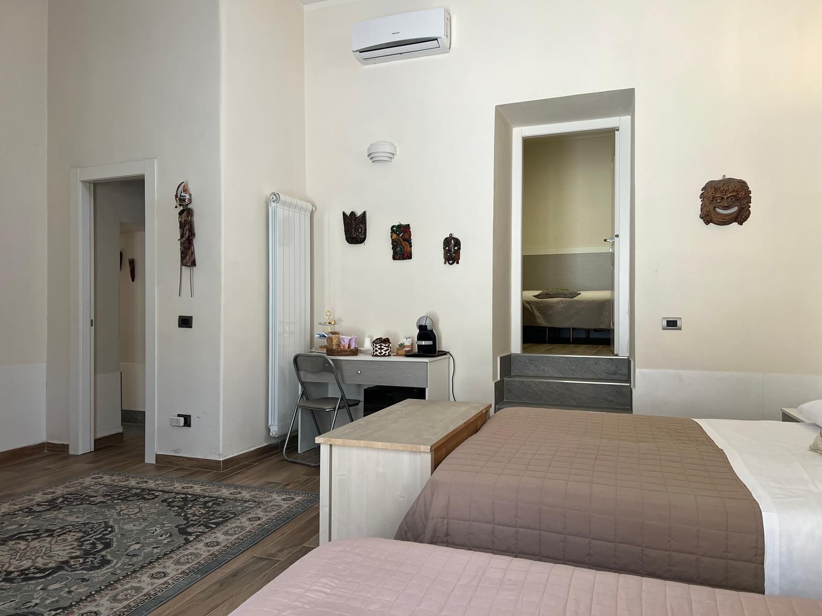 Una camera d'albergo con un letto, una scrivania, una sedia, un termosifone e una scala.