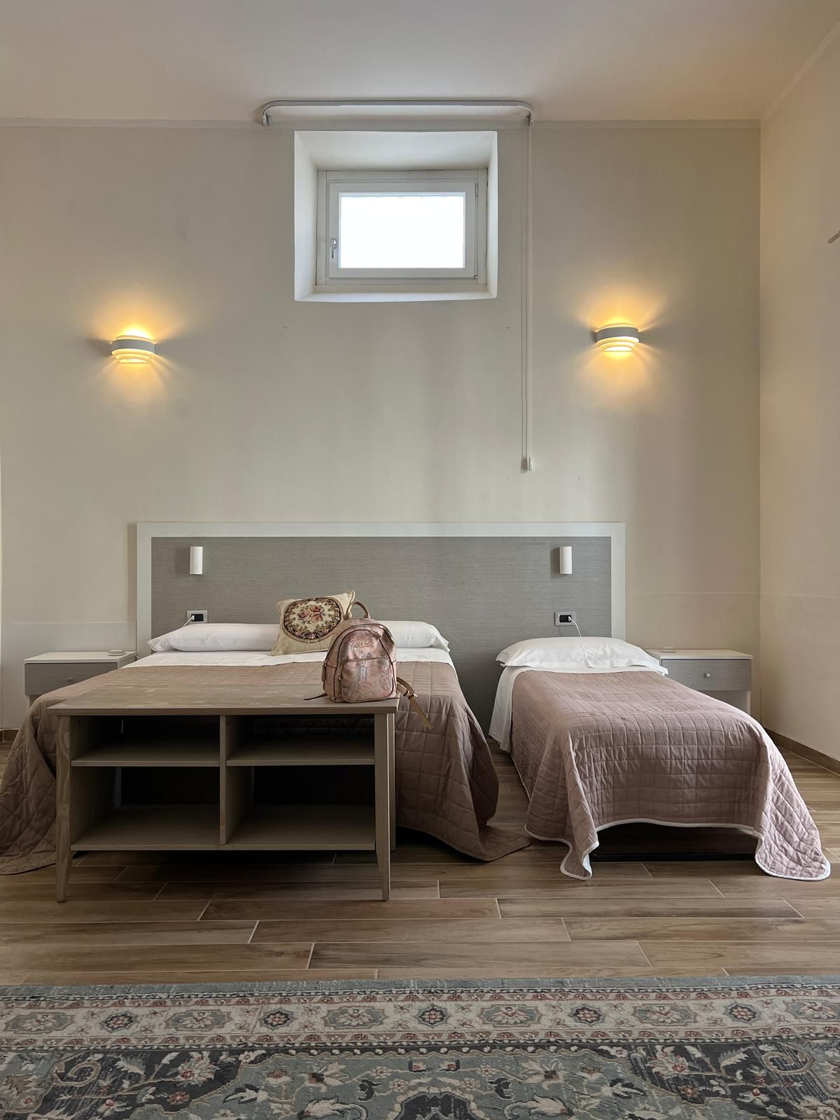 Ein Schlafzimmer mit zwei Betten, einem Oberlicht und Wandleuchten.