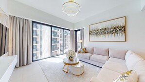 Una sala de estar moderna con un ventanal grande, un sofá, una mesa de centro y un cuadro en la pared.