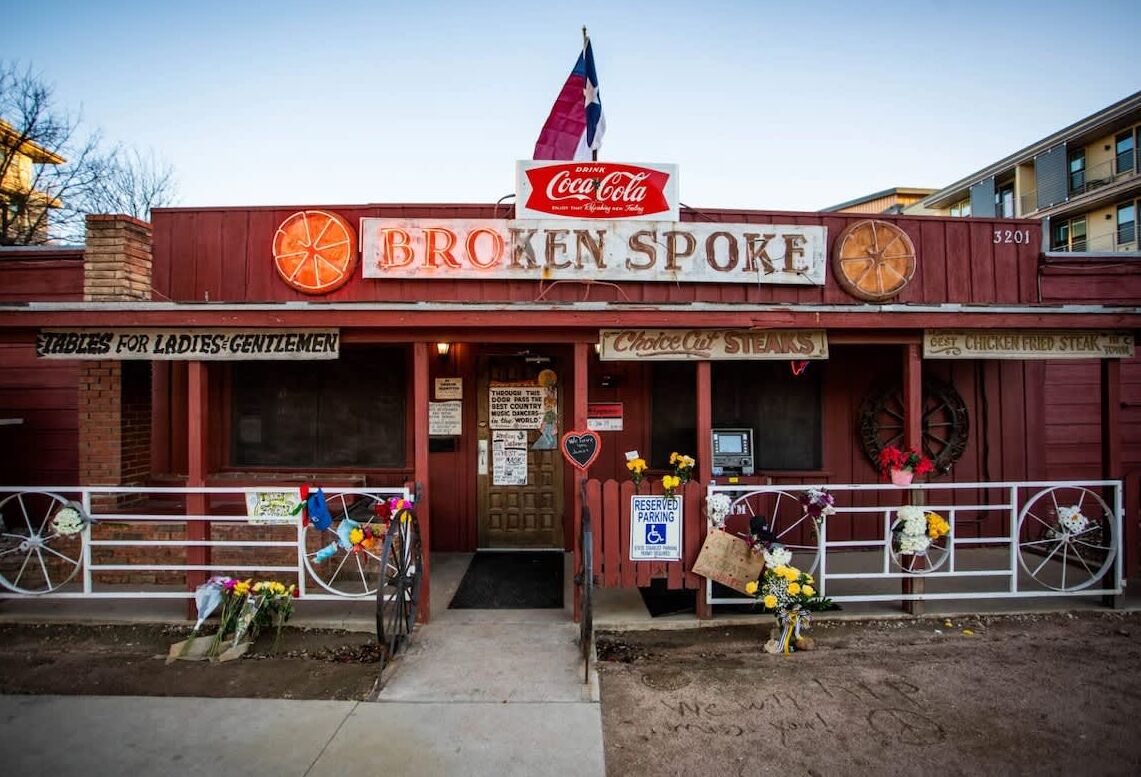 A vintage-themed building with a Coca-Cola sign, a sign reading "BROKEN SPOKE", and a "Choice Cut Steaks" sign.