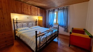 Une chambre avec un plafond en bois, un lit avec un cadre en métal, une commode et une fenêtre avec des rideaux.