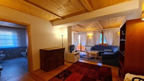 Un salon chaleureux avec un plafond en bois, un canapé, une table basse et un téléviseur. On y trouve également un meuble en bois et un tapis sur le sol.