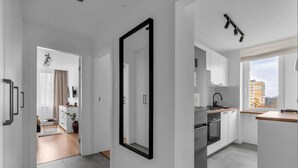 A modern kitchen with white cabinets, a built-in oven, and a window overlooking a cityscape.