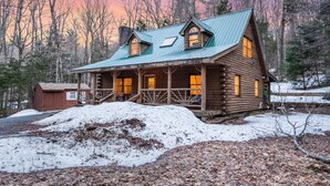 A log cabin with a porch, a small shed, and a snowy landscape. - Lucky Log Cabin- Hottub fireplace 12min to Mt Snow (Wardsboro)