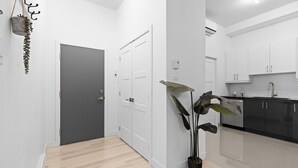 Una cocina moderna con armarios blancos, encimera negra y una planta en maceta.