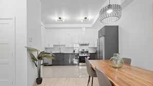 Una cocina moderna con armarios blancos, una mesa de comedor de madera y una lámpara colgante.