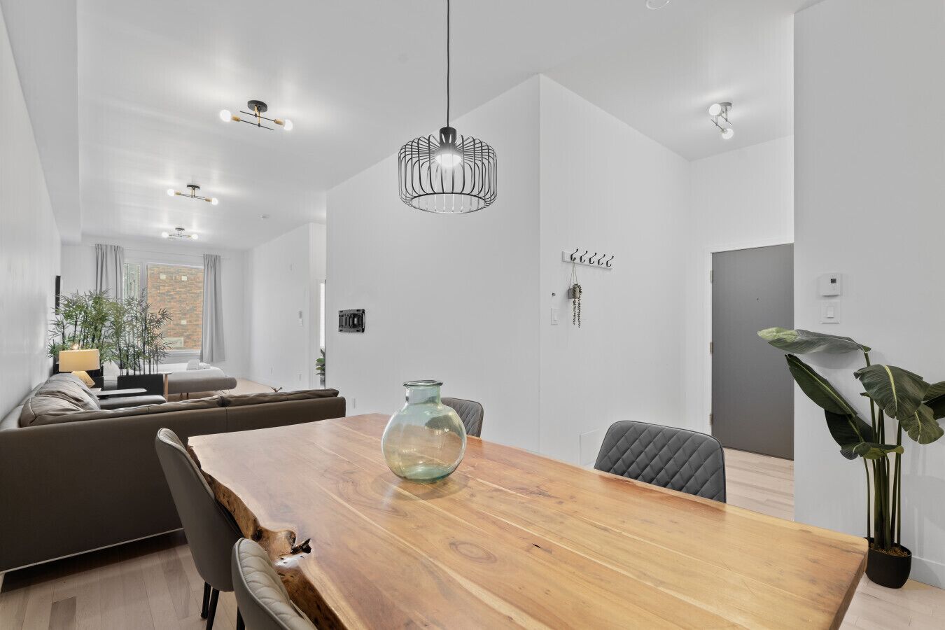 Een moderne eetruimte met een houten tafel, stoelen en een hanglamp.