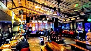 An indoor restaurant with high ceilings, exposed beams, and a bar area. - Walk to Zilker Barton Springs 5BR 3BA Villa Sleeps 14 (Austin)