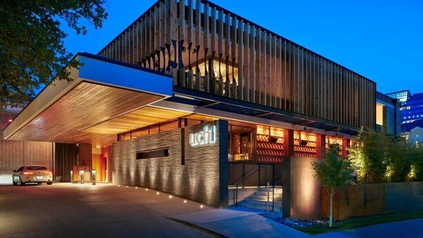 A modern building with a prominent 'UCHI' sign, a covered entrance, and a well-lit facade. - Walk to Zilker Barton Springs 5BR 3BA Villa Sleeps 14 (Austin)