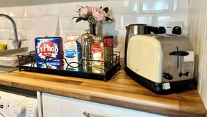 Una encimera de cocina con un tostador, una cafetera y varios cápsulas de café.