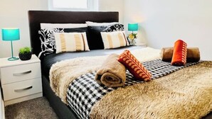 Un dormitorio ordenado con una cama, dos mesitas de noche y un ventanal.