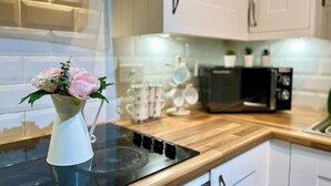 Una cocina con armarios blancos, un microondas y un florero con flores en la encimera.