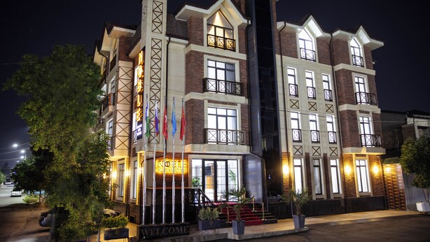 A multi-story hotel with a modern architectural design, featuring a prominent entrance with a red carpet and a 'WELCOME' sign. - Noble Samarkand (Samarkand)