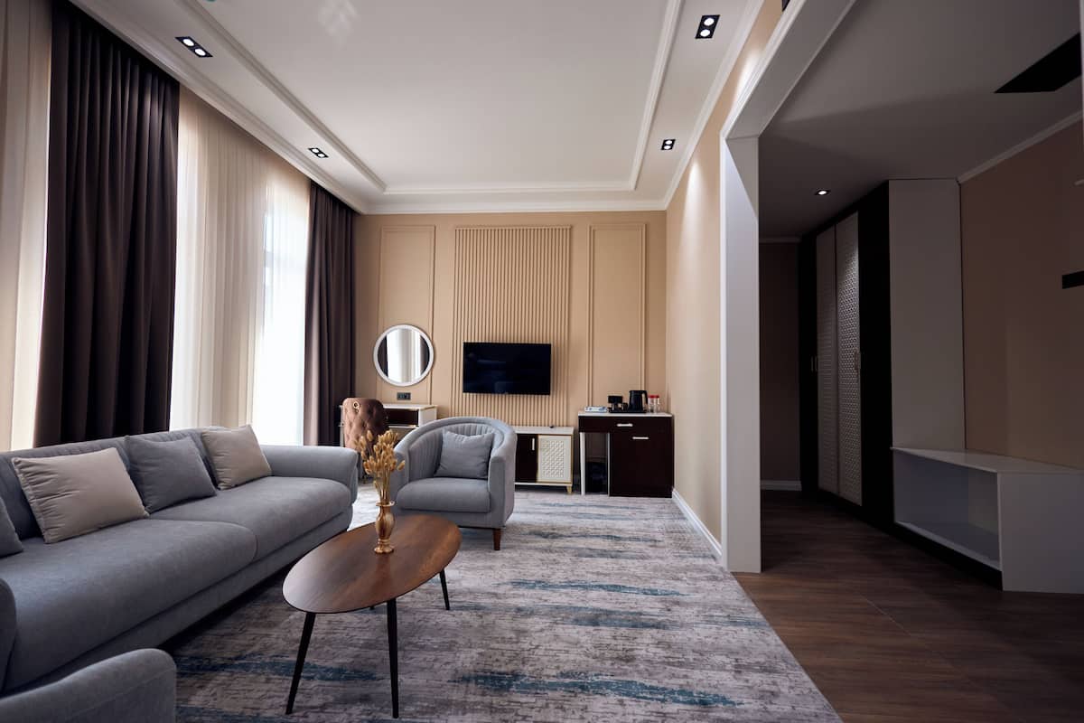 Egy modern nappali, amelyben van egy kanapé, egy fotel és egy dohányasztal, egy síkképernyős televízió, valamint egy íróasztal számítógéppel.