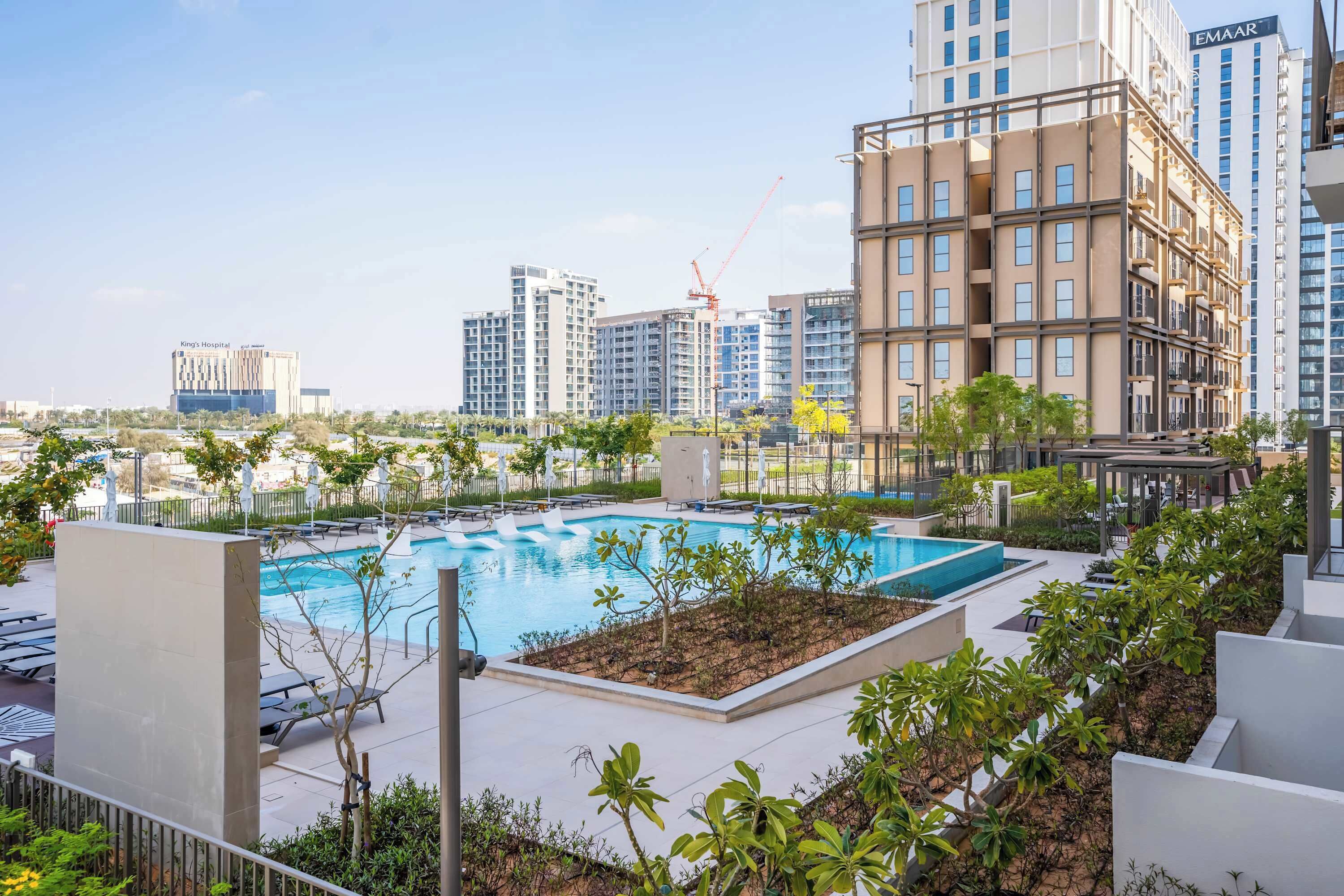 A rooftop pool area with lounge chairs and a view of surrounding high-rise buildings.