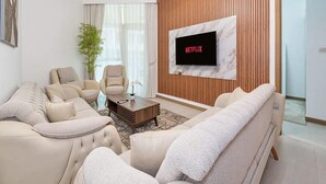 Una sala de estar moderna con un sofá color beige, una mesa de centro y un televisor de pantalla plana montado en una pared de madera.