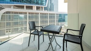 Un balcón con mesa y sillas, con vistas a un paisaje urbano de edificios modernos.