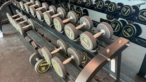 Estante con mancuernas en un gimnasio, con pesas de 5 a 16 kilogramos.