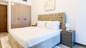 Une chambre d’hôtel avec un grand lit, une commode, une table de chevet avec une lampe et une porte.