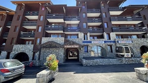 A multi-story hotel with a stone facade, balconies, and a sign for 'Le Creux de l'Ours'. - 40m from ski slopes, 5th floor, view valley, balcony, tv, 50m², Méribel-Mottaret (Méribel - Les Allues)