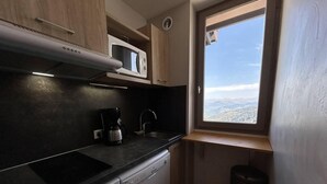 A compact kitchen with a microwave, coffee maker, and dishwasher. - 40m from ski slopes, 5th floor, view valley, balcony, tv, 50m², Méribel-Mottaret (Méribel - Les Allues)
