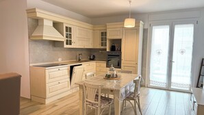 A compact kitchen with white cabinetry, a dining table with chairs, and a built-in oven.