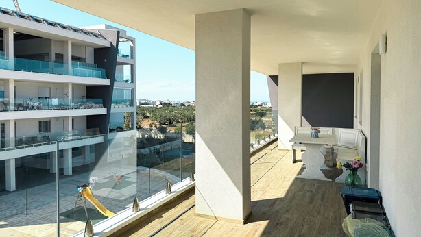 A modern apartment with a balcony, large windows, and a view of a cityscape.