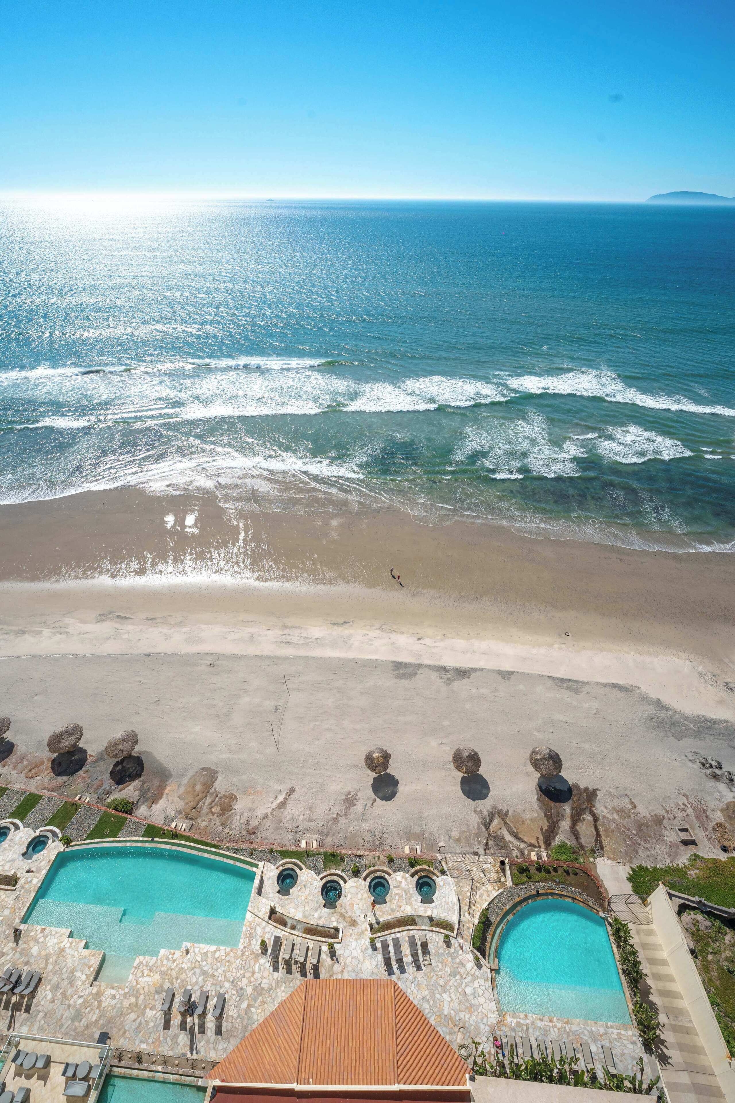 A resort with a large pool, a beach, and ocean views.