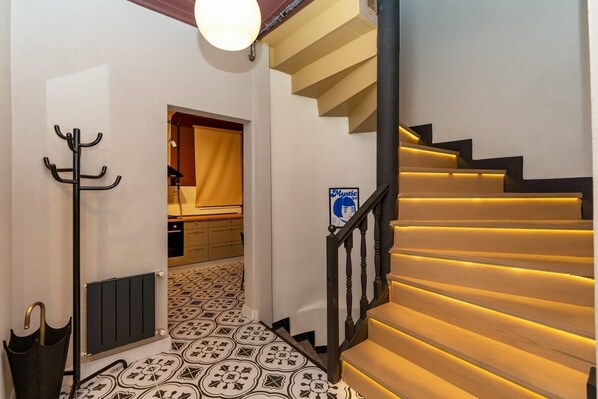 A staircase with illuminated steps, a coat rack, a radiator, and a patterned floor.