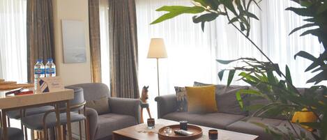 Una sala de estar con sofá, sillones, una mesa de centro y un comedor con sillas.