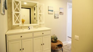 A bathroom with a white vanity, a large mirror, and a small wicker basket.