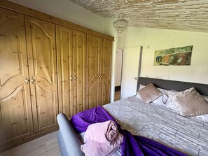 Un dormitorio con un amplio armario de madera, una cama con ropa de cama floral y una araña.