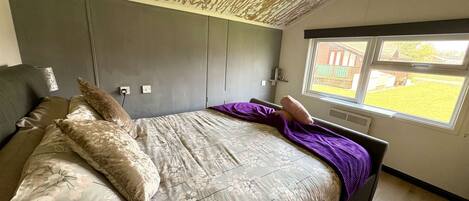 A bedroom with a bed, a window, and a view of the outside.