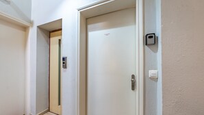 A hallway with a door, a wall-mounted light switch, and a doorbell.