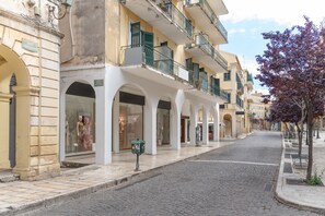 A cobblestone street with a row of buildings featuring balconies and storefronts.