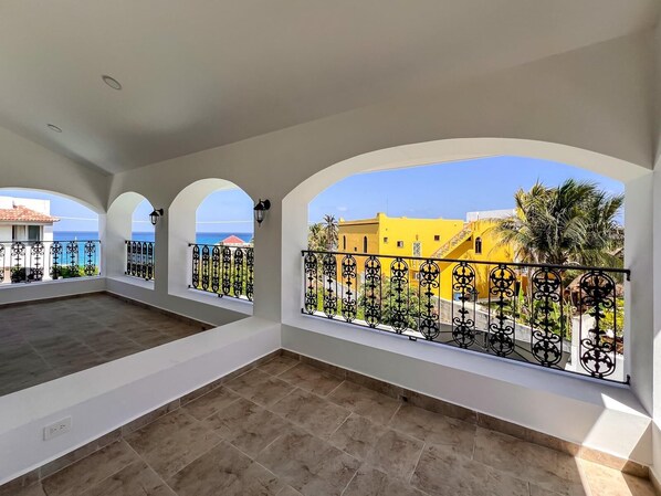 A balcony with a view of the sea and a yellow building. - Stunning 4bdr w/private pool in Punta Sur (Isla Mujeres)