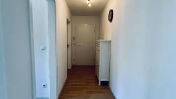 Ein Korridor mit Holzboden, weißen Wänden, einem Deckenventilator und einer Tür am Ende.
