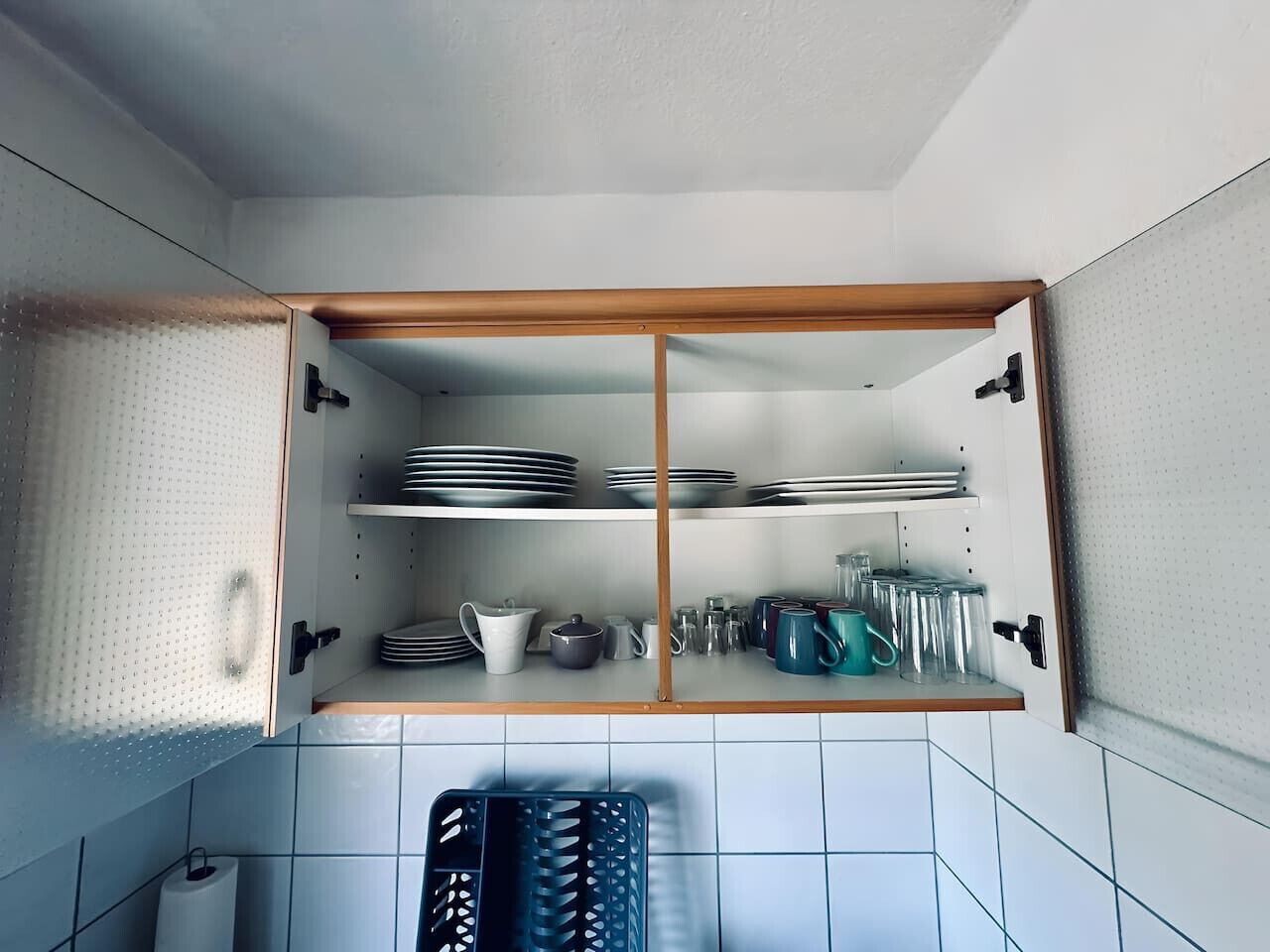 Una cocina con un mueble empotrado que contiene platos, tazones y tazas.