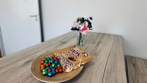 A wooden table with a plate of colorful candies and a chocolate bar. - Apartment Euregio III - Central & close to the clinic (Nordhorn)