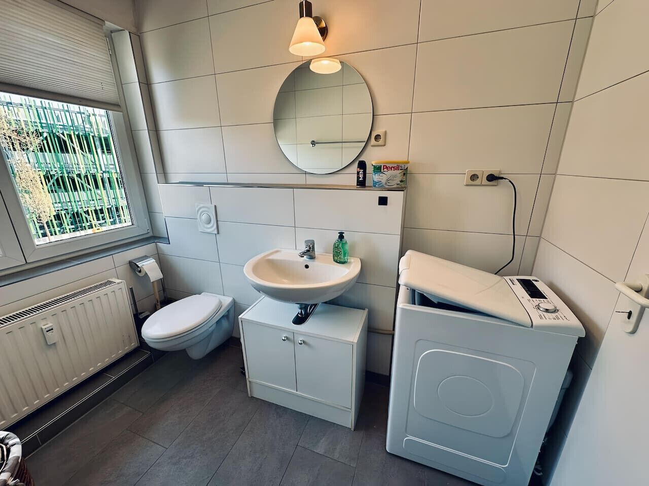 A modern bathroom with a toilet, sink, and washing machine.