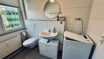 A modern bathroom with a toilet, sink, and washing machine.